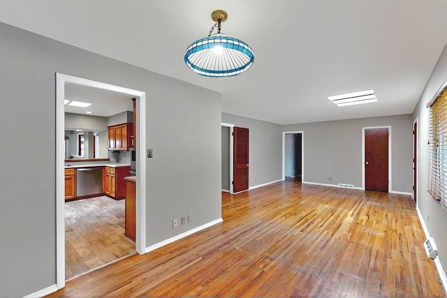 unfurnished living room featuring baseboards, visible vents, and light wood-style floors