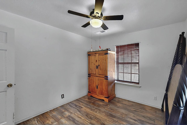 spare room with a ceiling fan, baseboards, visible vents, and dark wood-style floors