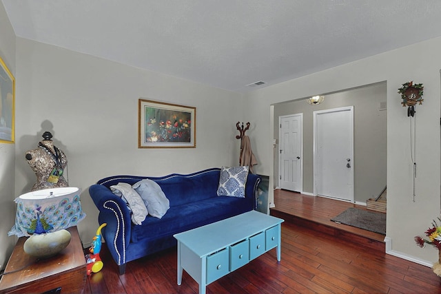 living room with baseboards, visible vents, and hardwood / wood-style flooring