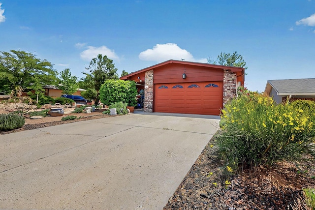 view of front of house featuring a garage, driveway, and stone siding