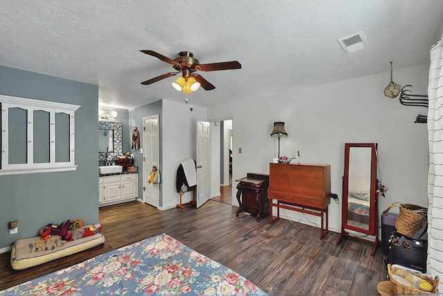 bedroom featuring dark wood finished floors, a ceiling fan, baseboards, ensuite bathroom, and visible vents