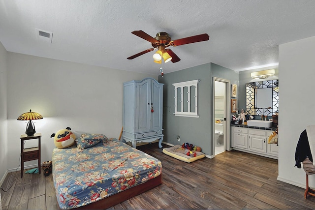 bedroom with visible vents, baseboards, dark wood-style floors, a sink, and ensuite bath