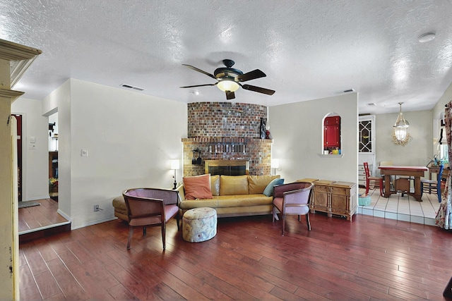 living room with wood-type flooring, visible vents, baseboards, ceiling fan, and a textured ceiling