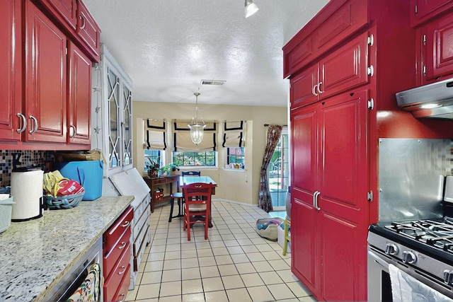 kitchen with stainless steel gas range, decorative backsplash, light tile patterned floors, under cabinet range hood, and visible vents