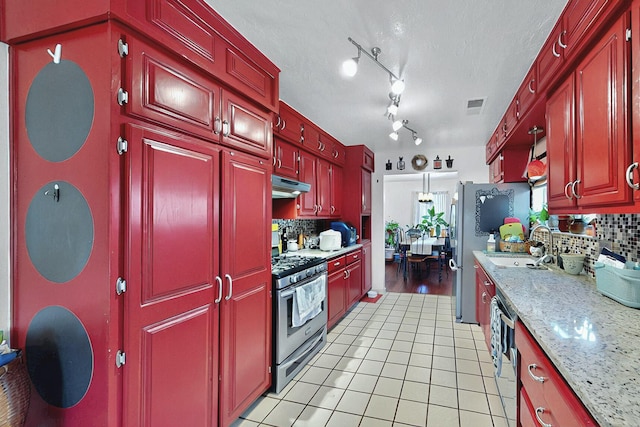 kitchen with decorative backsplash, visible vents, appliances with stainless steel finishes, light tile patterned floors, and under cabinet range hood