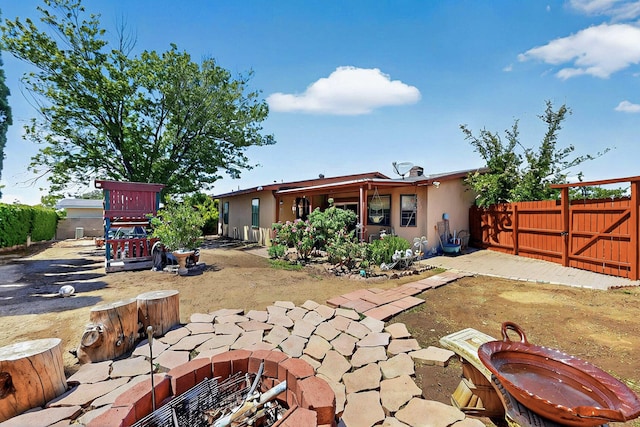 rear view of house featuring a patio area, stucco siding, and fence