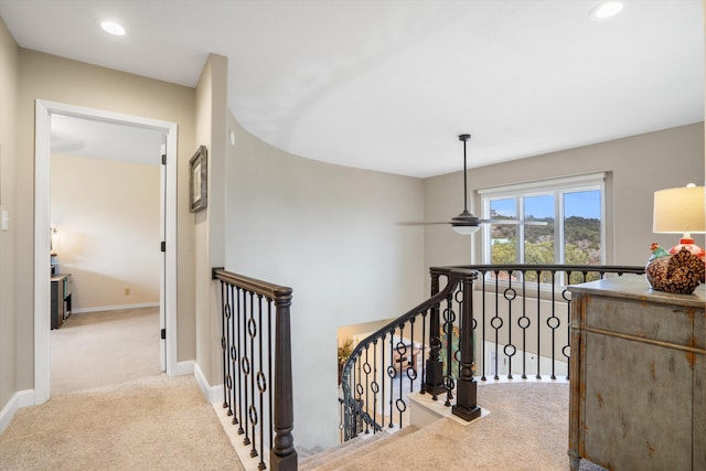 hall featuring carpet floors, recessed lighting, baseboards, and an upstairs landing