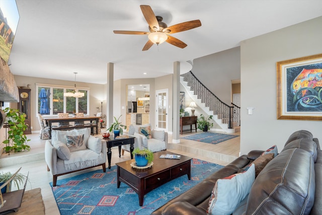living area featuring baseboards, a ceiling fan, wood finished floors, and stairway