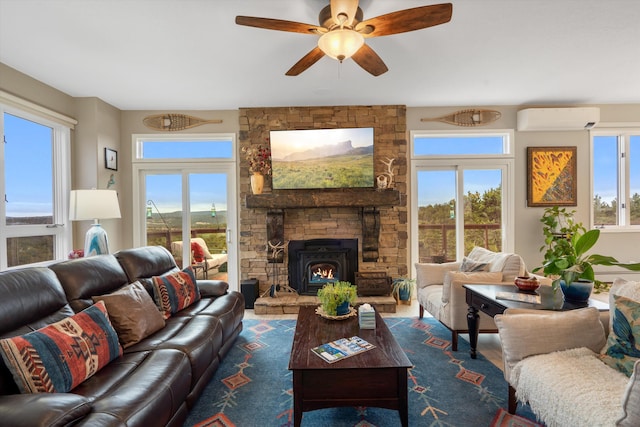 living area with a stone fireplace, ceiling fan, a wall mounted AC, and wood finished floors