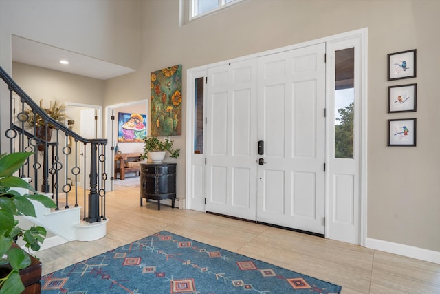 entryway with baseboards, a high ceiling, stairs, and wood finished floors