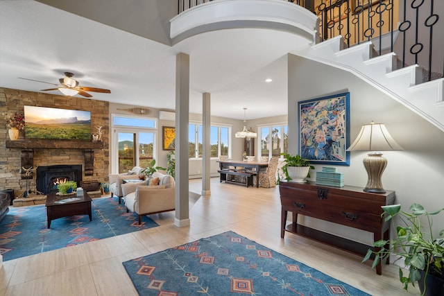 interior space with stairway, light tile patterned floors, ceiling fan with notable chandelier, and a fireplace