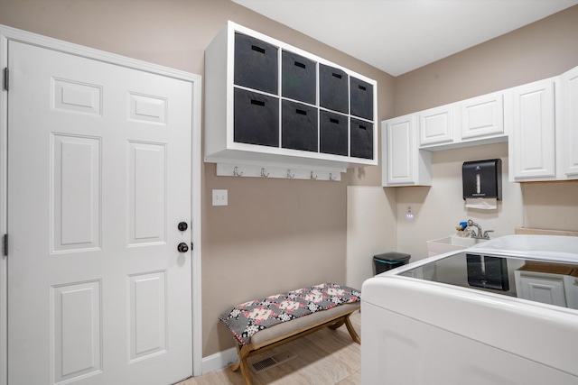 laundry room with baseboards, washer / dryer, a sink, and light wood-type flooring