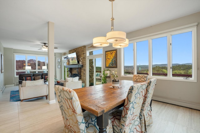 dining space with a fireplace, baseboards, ceiling fan, a baseboard radiator, and light wood finished floors