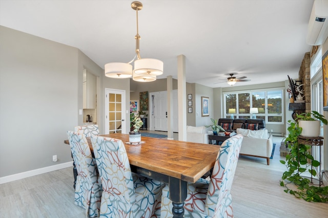 dining area with light wood-style flooring, a ceiling fan, baseboards, a wall unit AC, and a baseboard radiator