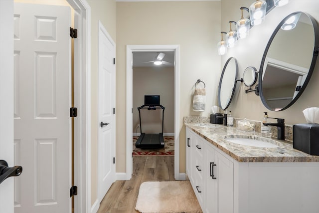 full bath featuring double vanity, baseboards, a sink, and wood finished floors