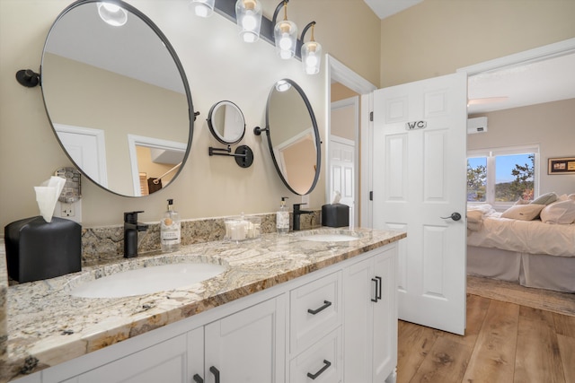 ensuite bathroom featuring double vanity, a sink, ensuite bathroom, and wood finished floors