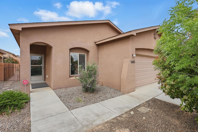 view of front of home with stucco siding, a garage, and fence