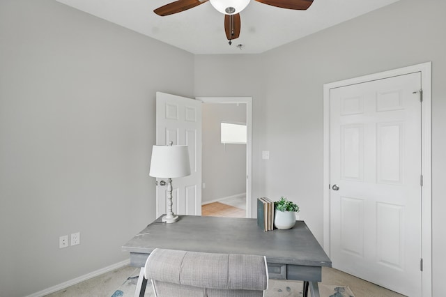 office area with light carpet, baseboards, and a ceiling fan