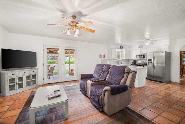 living room featuring a ceiling fan, a textured ceiling, light tile patterned flooring, and french doors
