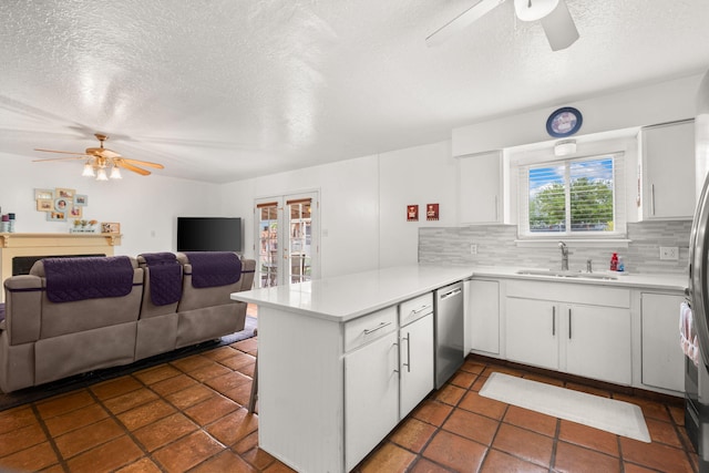 kitchen featuring ceiling fan, a sink, a peninsula, a textured ceiling, and stainless steel dishwasher