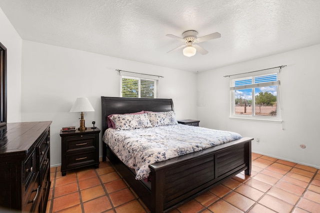 bedroom featuring light tile patterned floors, a textured ceiling, a ceiling fan, and baseboards