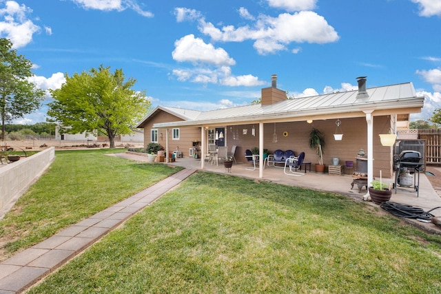 rear view of property with a patio area, a chimney, metal roof, and a standing seam roof