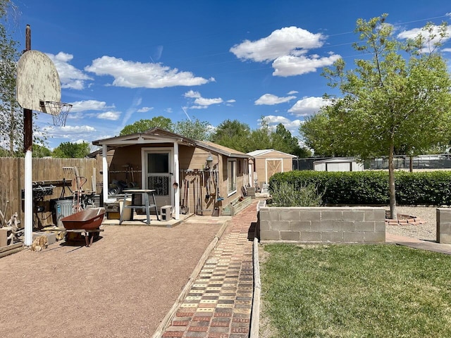 back of property featuring an outdoor structure, fence, a lawn, and a shed