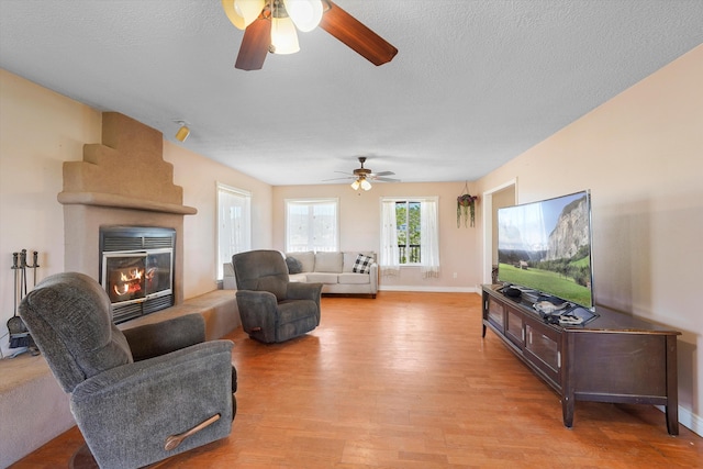 19 Sage Ct, Edgewood, NM 87015 - living room with a ceiling fan, light wood-style floors, a large fireplace, baseboards, and a textured ceiling
