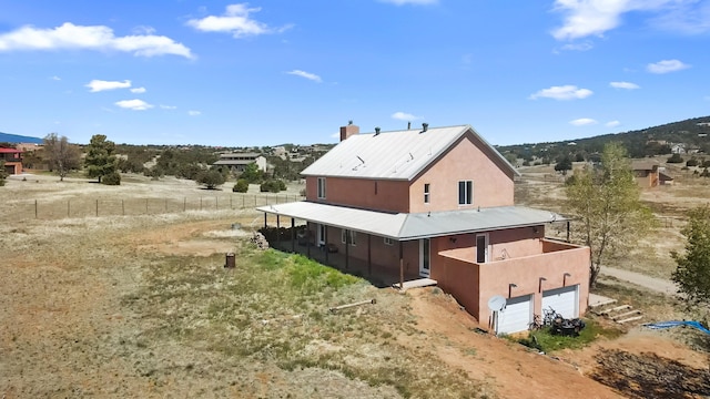 19 Sage Ct, Edgewood, NM 87015 - back of house featuring stucco siding, a garage, metal roof, a chimney, and driveway