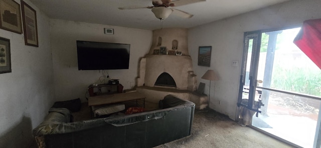 carpeted living area with a ceiling fan and a large fireplace