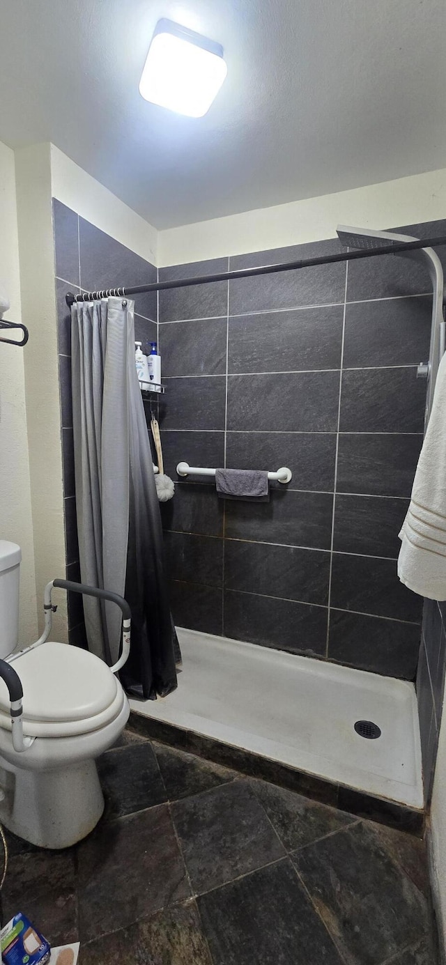 full bathroom featuring a shower stall and toilet