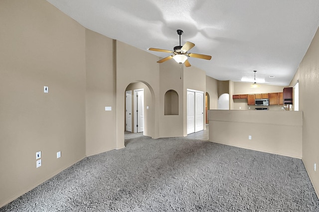 unfurnished living room featuring arched walkways, light colored carpet, ceiling fan, baseboards, and high vaulted ceiling