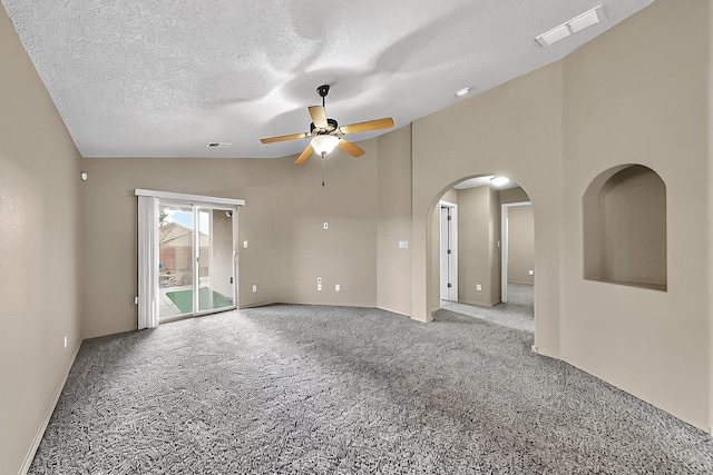 carpeted empty room with lofted ceiling, ceiling fan, arched walkways, baseboards, and a textured ceiling