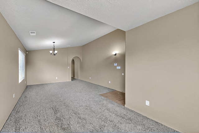 spare room featuring carpet, arched walkways, and a chandelier
