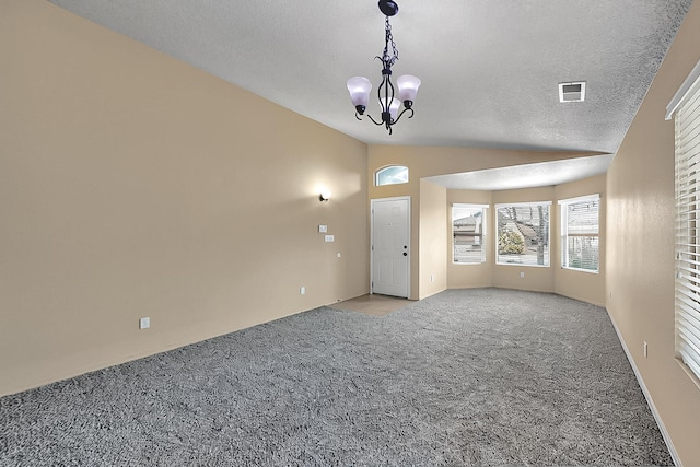 spare room featuring vaulted ceiling, light carpet, a chandelier, and a textured ceiling