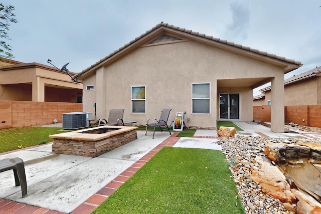 rear view of property with cooling unit, stucco siding, a patio area, and an outdoor fire pit