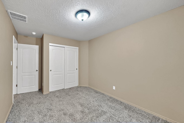 unfurnished bedroom with carpet flooring, a closet, baseboards, and a textured ceiling