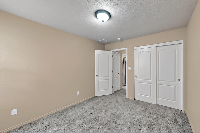 unfurnished bedroom featuring carpet, a closet, a textured ceiling, and baseboards