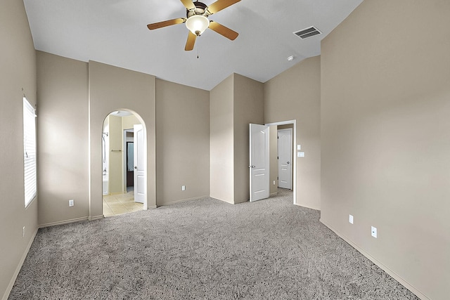 7229 Skagway Dr NE, Rio Rancho, NM 87144 - unfurnished bedroom with high vaulted ceiling, arched walkways, light carpet, baseboards, and ensuite bath