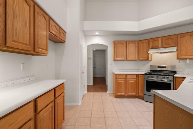 2105 Gila River Rd NE, Rio Rancho, NM 87144 - kitchen featuring gas range, under cabinet range hood, light countertops, a towering ceiling, and brown cabinets