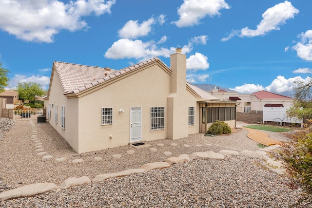 2105 Gila River Rd NE, Rio Rancho, NM 87144 - rear view of house featuring a chimney, fence, stucco siding, and a tile roof