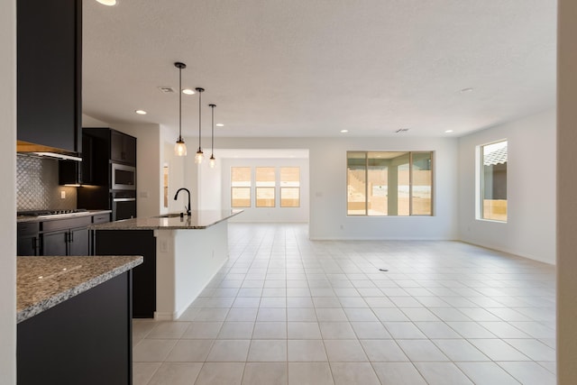 6791 Sydney Dr NE, Rio Rancho, NM 87144 - kitchen with black appliances, open floor plan, tasteful backsplash, a sink, and an island with sink