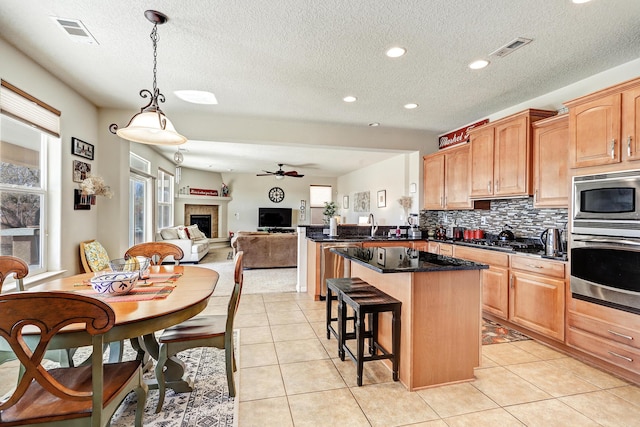 15 Los Miradores Dr NE, Rio Rancho, NM 87124 - kitchen with appliances with stainless steel finishes, a center island, a breakfast bar, decorative backsplash, and ceiling fan