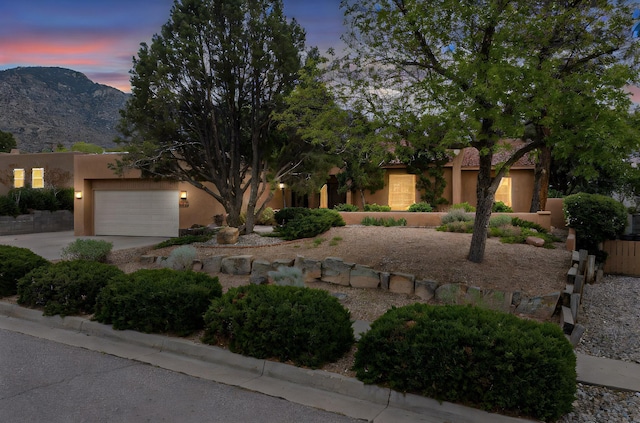 13108 Della Longa Ln NE, Albuquerque, NM 87111 - pueblo-style house with stucco siding, concrete driveway, an attached garage, and a mountain view