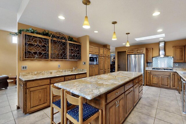 13108 Della Longa Ln NE, Albuquerque, NM 87111 - kitchen featuring wall chimney range hood, appliances with stainless steel finishes, brown cabinets, light tile patterned flooring, and recessed lighting