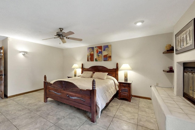 13108 Della Longa Ln NE, Albuquerque, NM 87111 - bedroom featuring a glass covered fireplace, baseboards, ceiling fan, and light tile patterned floors
