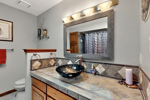 13108 Della Longa Ln NE, Albuquerque, NM 87111 - full bath with toilet, vanity, tasteful backsplash, and vaulted ceiling
