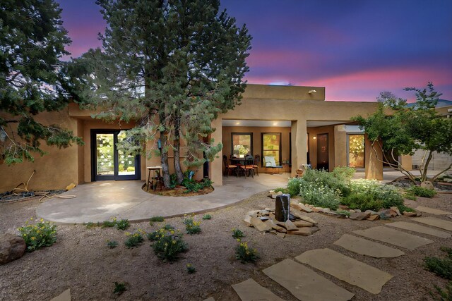 13108 Della Longa Ln NE, Albuquerque, NM 87111 - back of house at dusk with stucco siding, french doors, and a patio