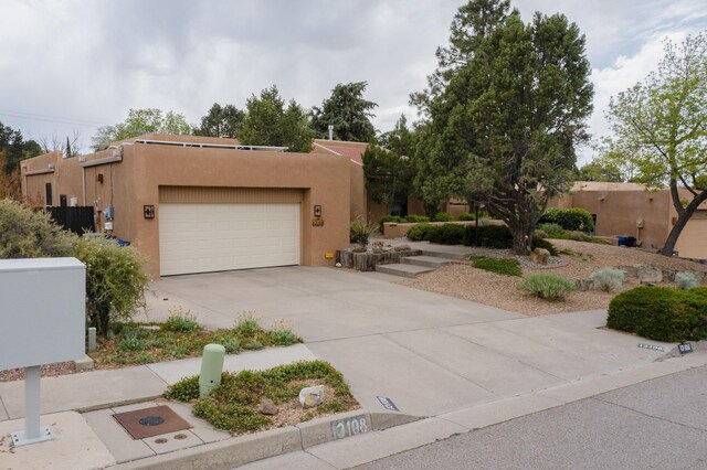 13108 Della Longa Ln NE, Albuquerque, NM 87111 - adobe home with a garage, concrete driveway, and stucco siding