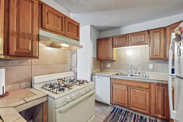 2800 Vail Ave SE Unit D113, Albuquerque, NM 87106 - kitchen with white appliances, under cabinet range hood, a sink, tile countertops, and backsplash